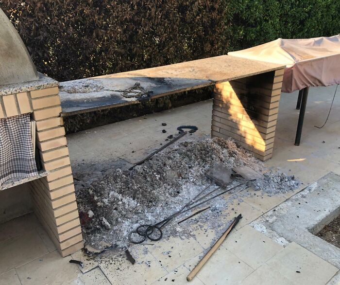 Outdoor kitchen barbecue area covered with ashes and burnt debris after fire fail
