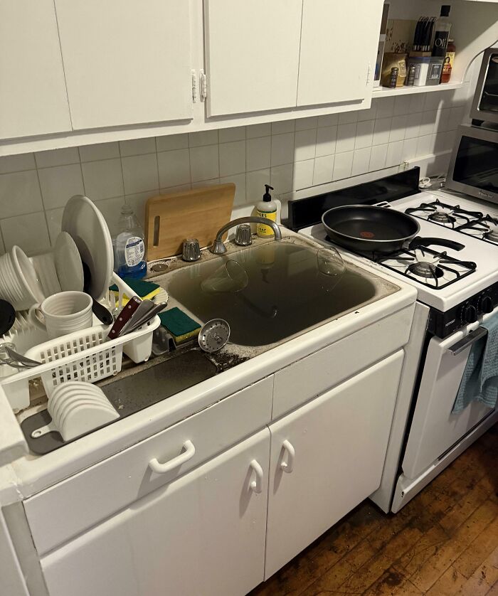 Sink filled with dirty water next to gas stove kitchen plumbing fail