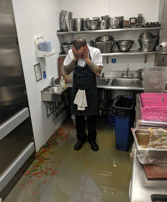 Frustrated chef standing in kitchen flooded with spilled food and liquid