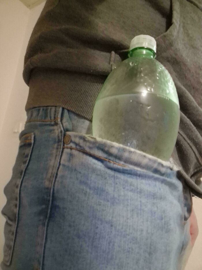 Water bottle tucked into back pocket of denim jeans