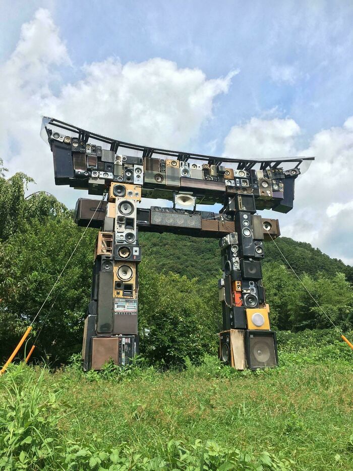 Torii gate sculpture made from stacked speakers in outdoor setting
