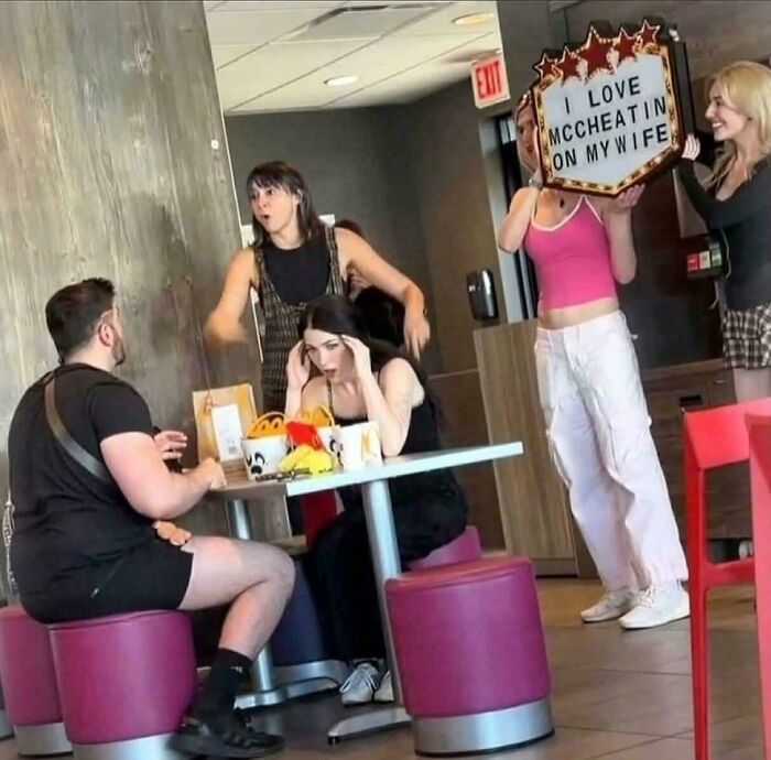 Man confronted in restaurant while woman holds sign hmm image