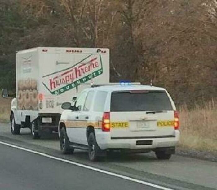 State police car pulling over Krispy Kreme delivery truck on road
