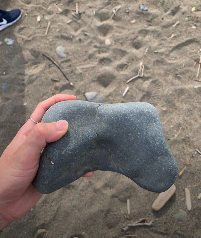 Hand holding a strangely shaped stone resembling a video game controller in hmmm images