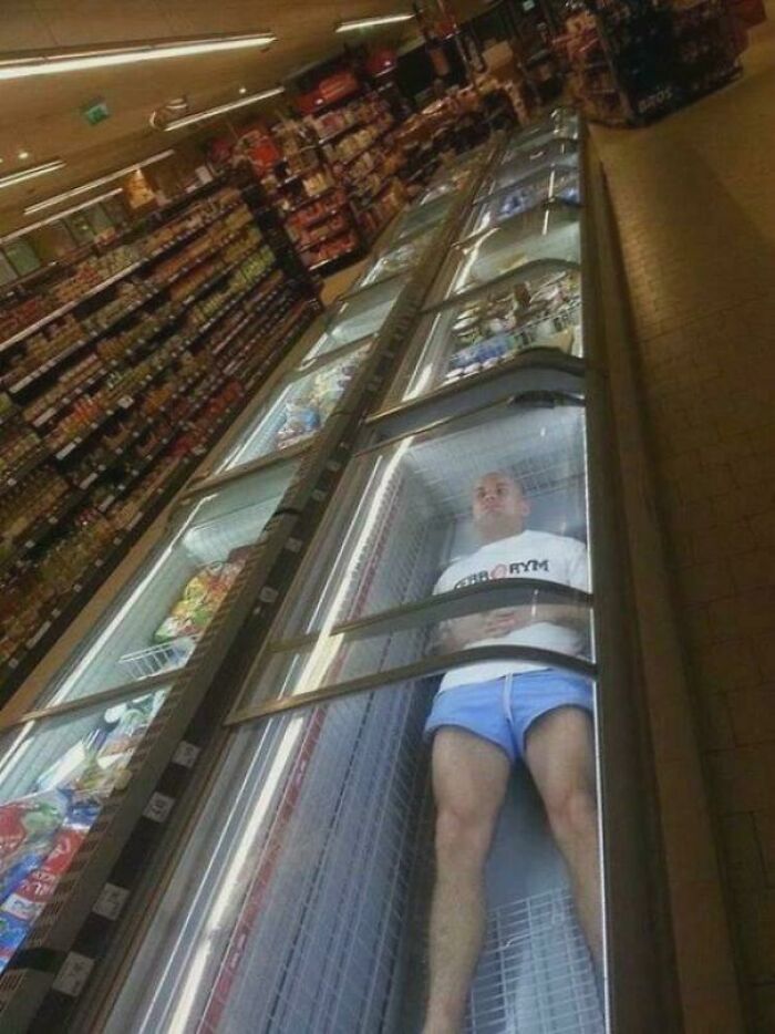 Person lying inside a supermarket freezer in frozen foods aisle
