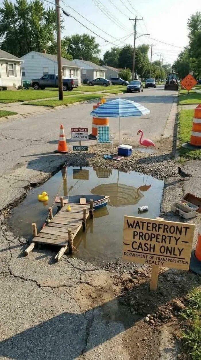 Creative street pothole setup mimics waterfront property with dock and boat
