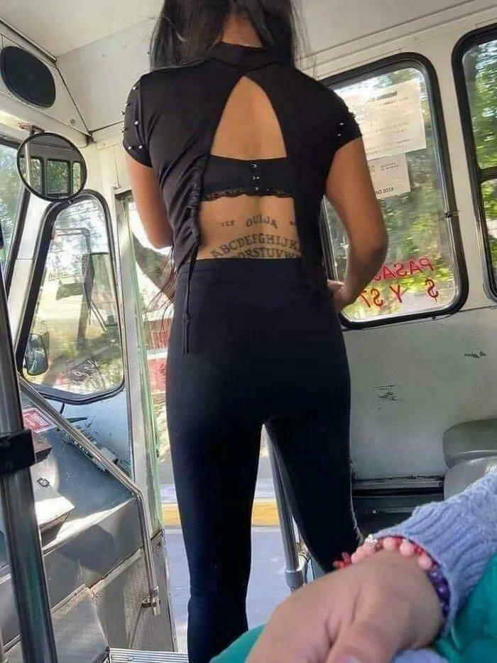 Person wearing black outfit with back cutout revealing Ouija board tattoo
