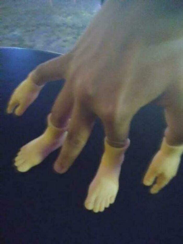 Human hand wearing tiny gloves shaped like feet hmmm image