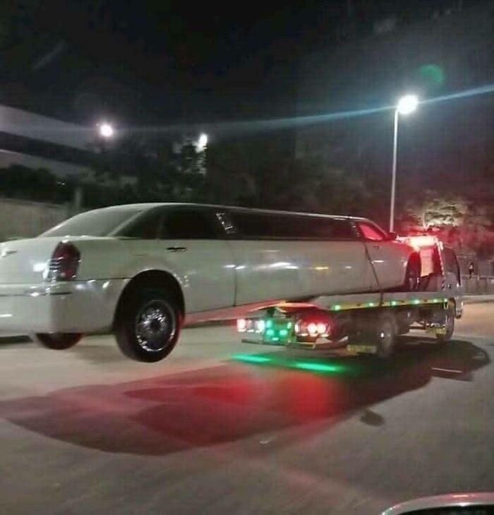 Limousine loaded on tow truck lit at night on city street