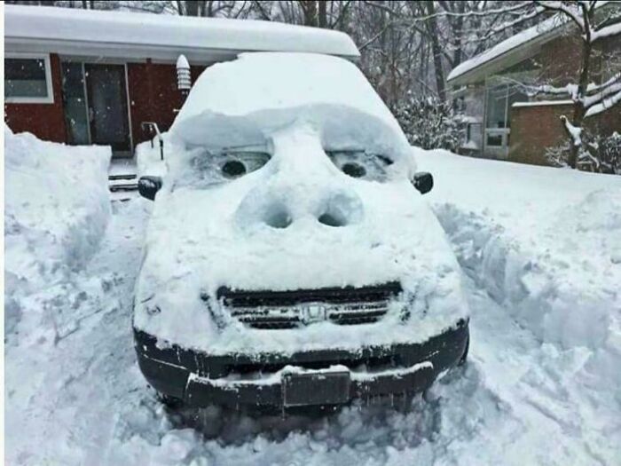 Car covered in snow sculpted to look like a gorilla face in winter