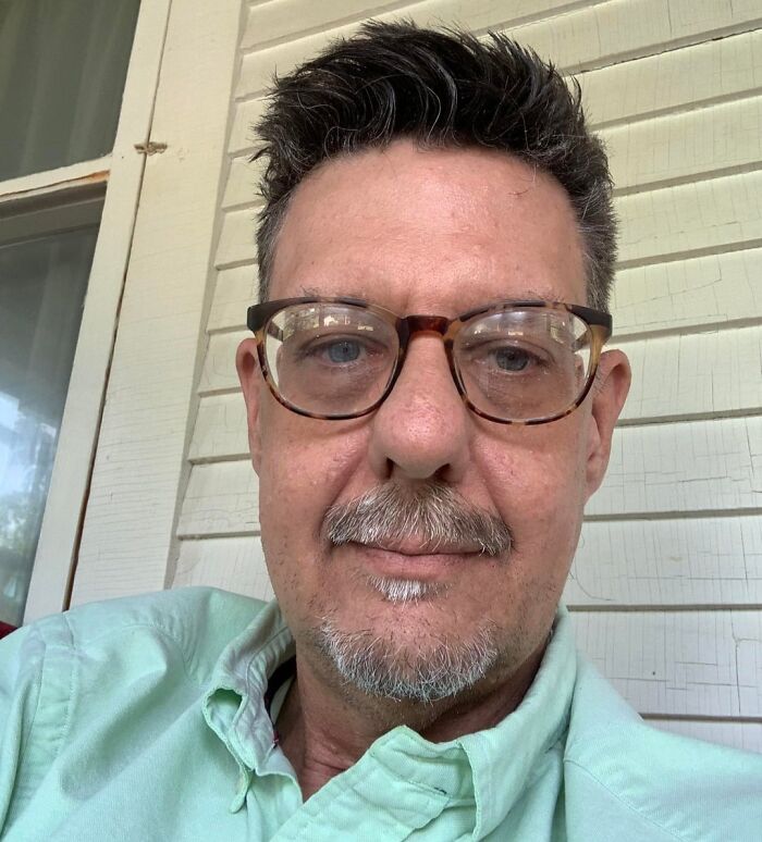 Selfie of a man with glasses sitting on a porch