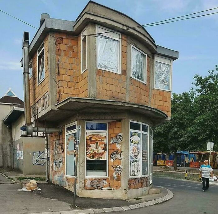 Small quirky urban hell corner building with unfinished brick walls and graffiti