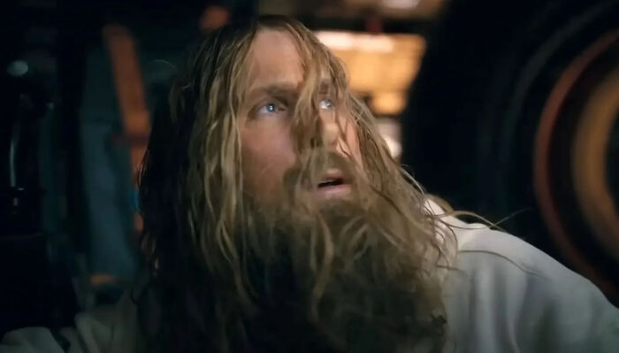 A man with long, wet hair and a beard looks up with a surprised expression, highlighting hilarious movie details.