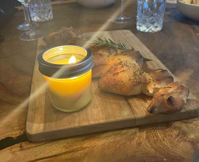 Rustic herb bread with a lit candle on wooden serving board