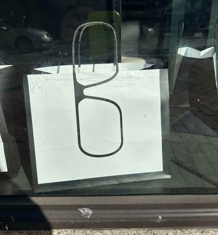 White paper bag with black eyeglass frame print on store window