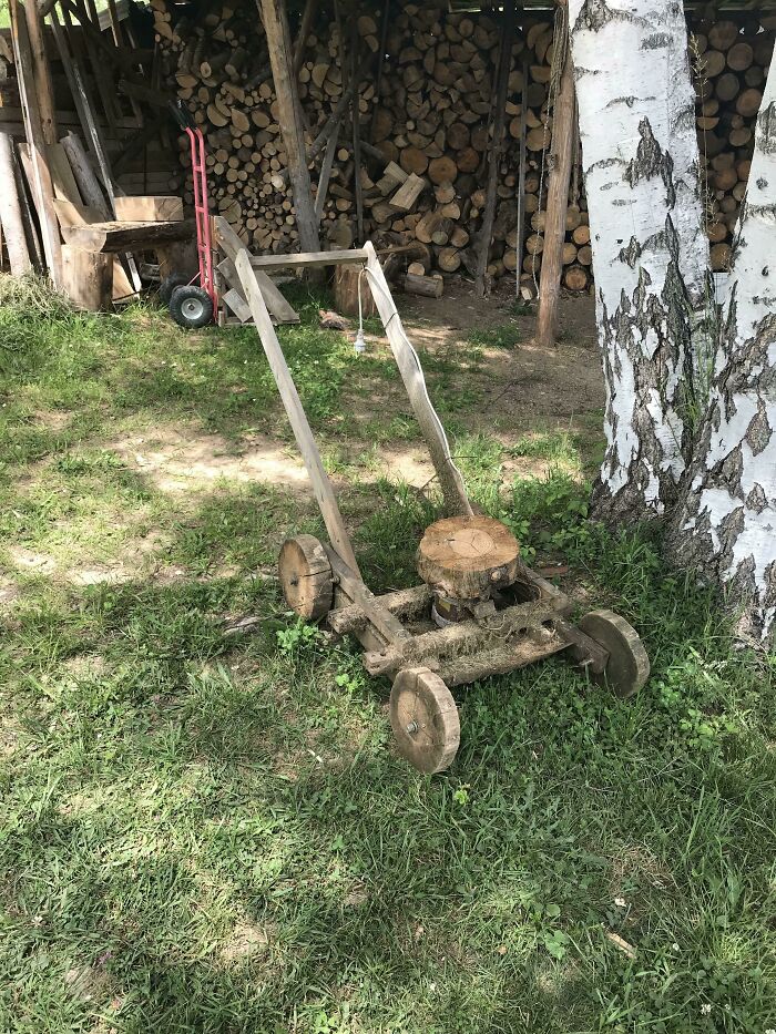 Low-tech wooden push mower built from scrap materials on grass