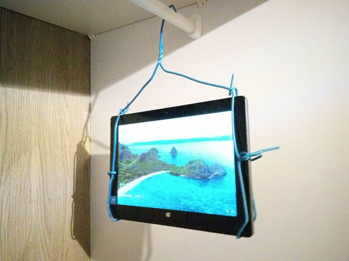 DIY hanging tablet holder made with wire hanger in corner low-tech solution