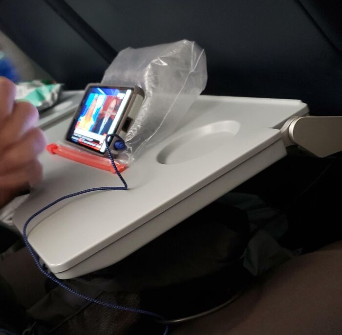 Low-tech phone holder made with plastic bag cushioning on airplane tray