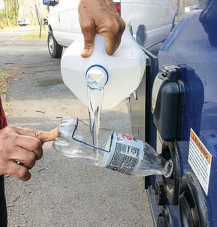 Low-tech fuel pouring trick using cut plastic bottle as funnel attached to gas tank