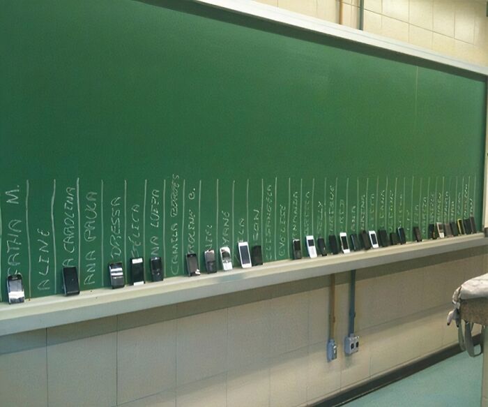 Low-tech solution for phone charging spots labeled on chalkboard classroom shelf