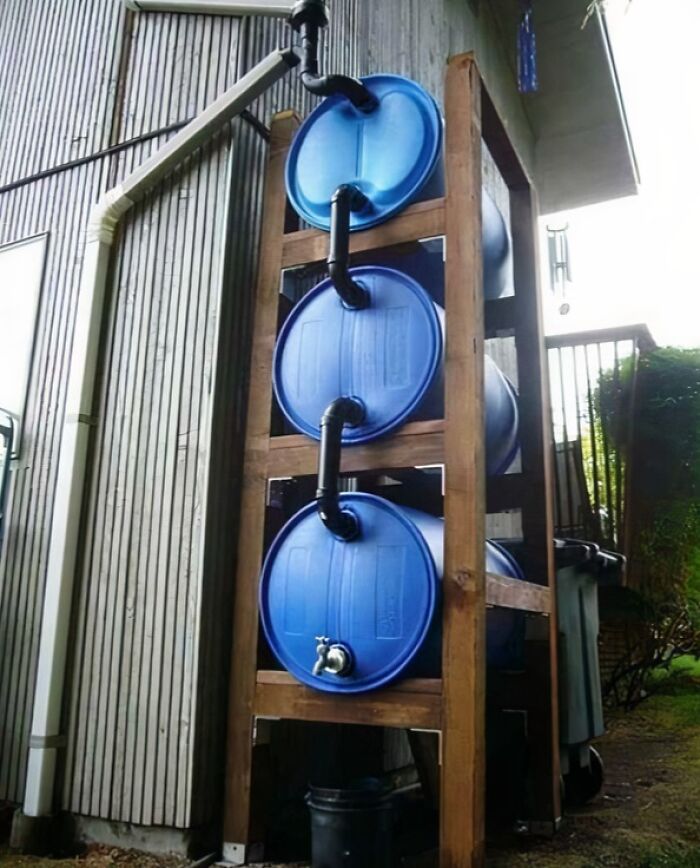Stacked rain barrels connected with pipes for low-tech water collection system
