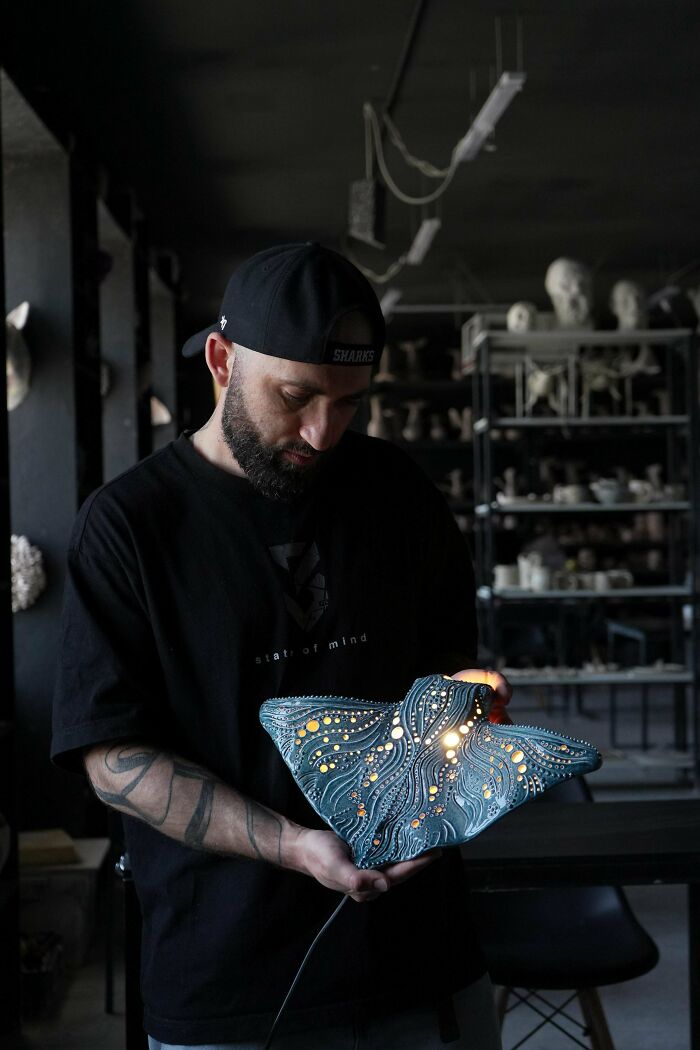 A person holding a unique handmade stingray-shaped lamp, demonstrating talent in handmade projects.