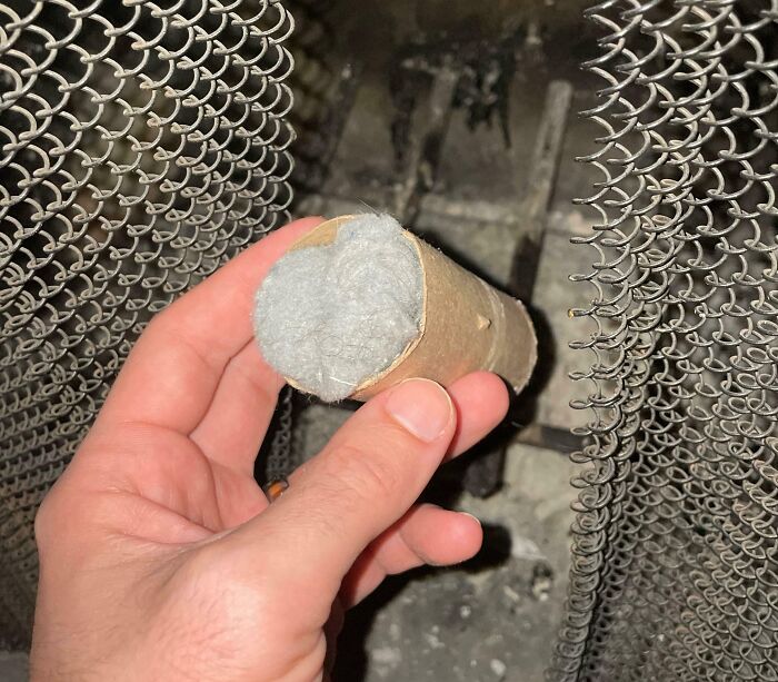 Hand holding dryer lint wrapped in a cardboard tube as cleaning hack