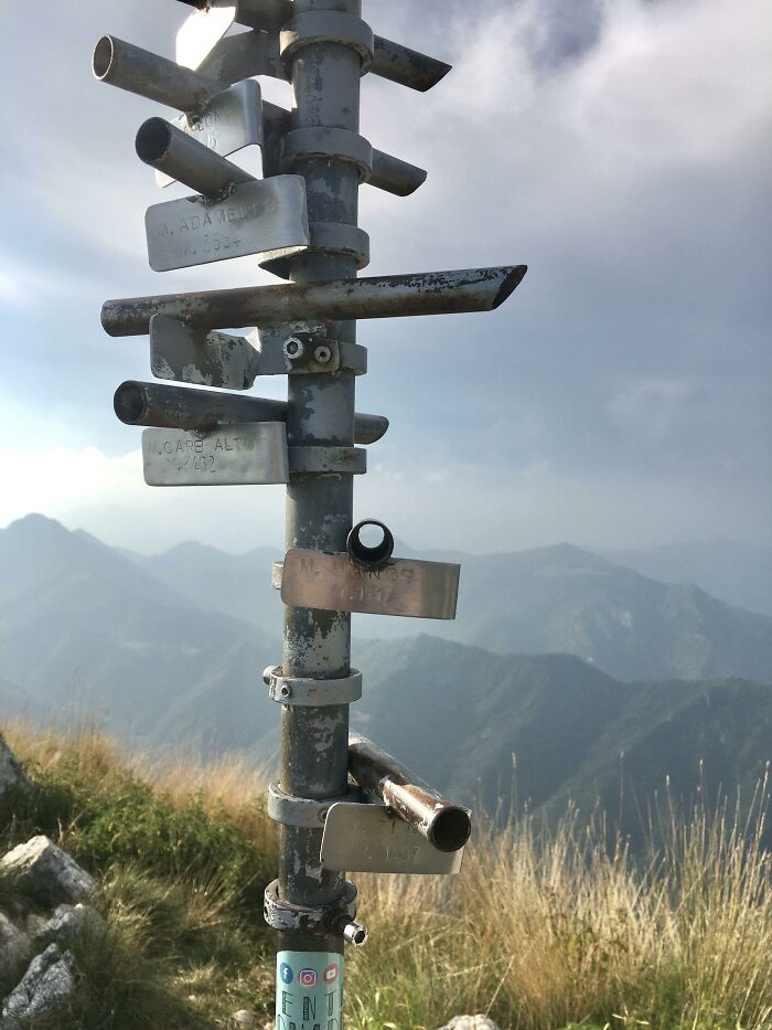 Metal directional signs on a mountain hiking trail with scenic background