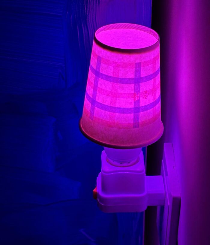 Purple bedside lamp with a patterned lampshade plugged into power socket