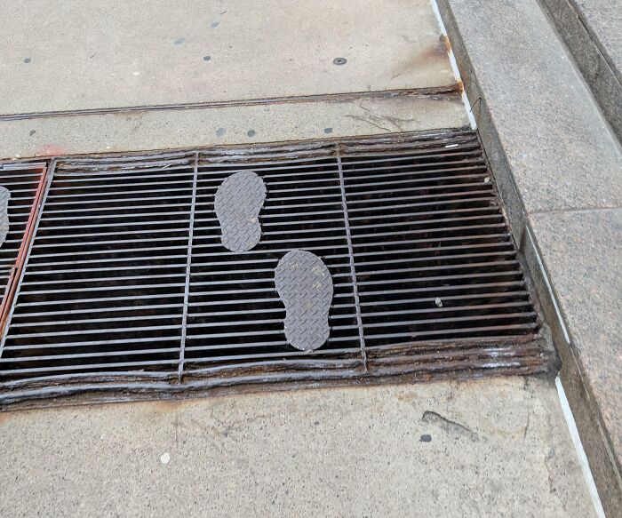 Footprint-shaped metal plates on a street grate improving safety
