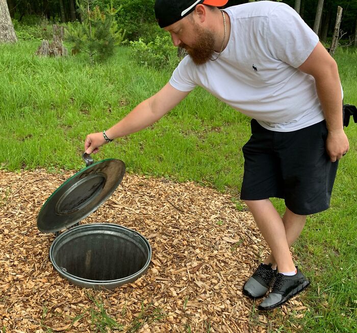 Man opening an innovative hidden trash bin in outdoor area