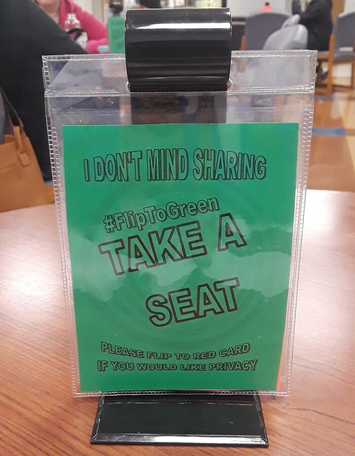 Sign encouraging shared seating in school with flip card for privacy option