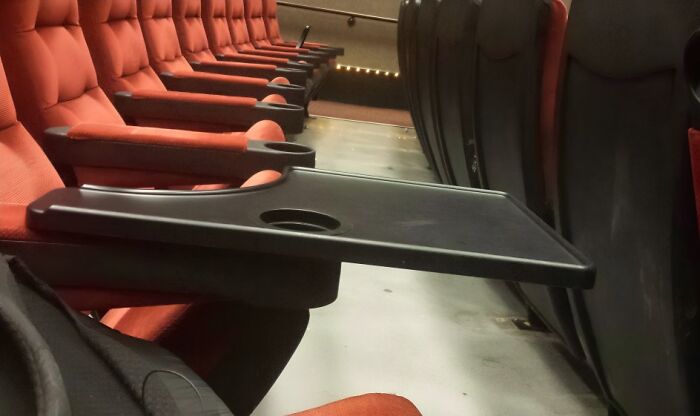 Rows of red cushioned seats with foldable trays in university lecture hall