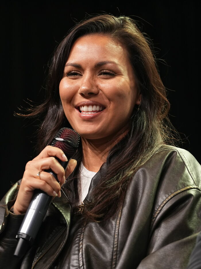 Close-up of Olivia Olson smiling and holding a microphone during a speaking event