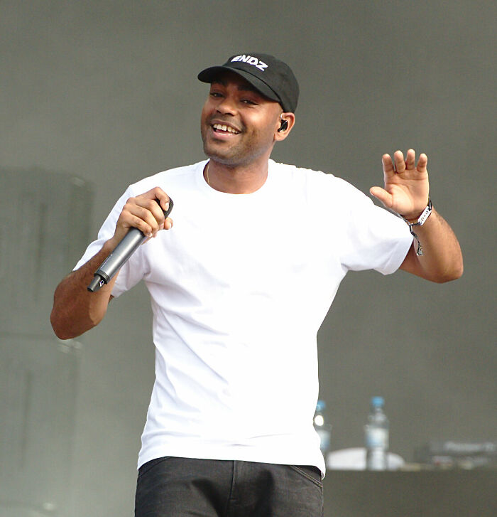 Kano performing on stage with a microphone, showcasing his music career highlights