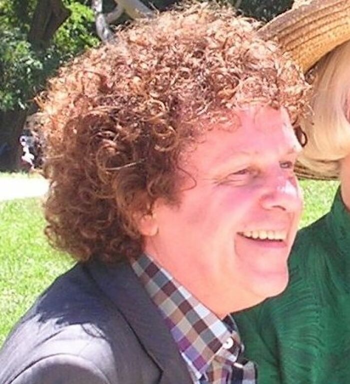 Portrait of Leo Sayer with curly hair smiling outdoors