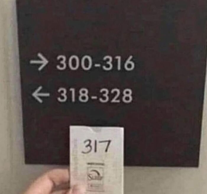 Confusing directional sign with handwritten room number 317 between two ranges