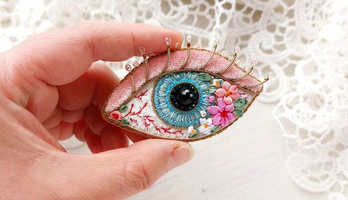 A hand-made beaded eye brooch representing unique embroidery projects, decorated with pink and blue details