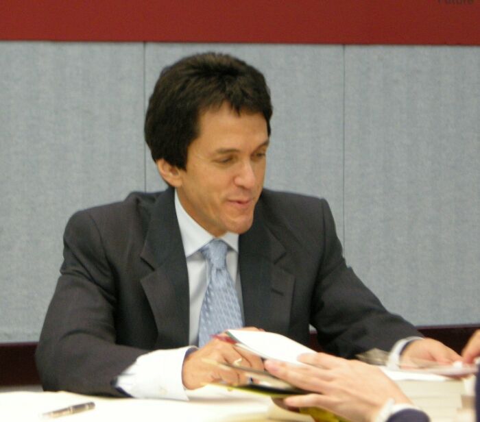 Mitch Albom signing books at an event, showcasing key moments in his writing career