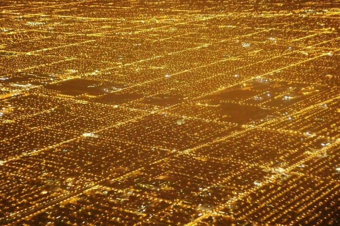 Aerial view of urban hell at night showing endless yellow streetlights grid