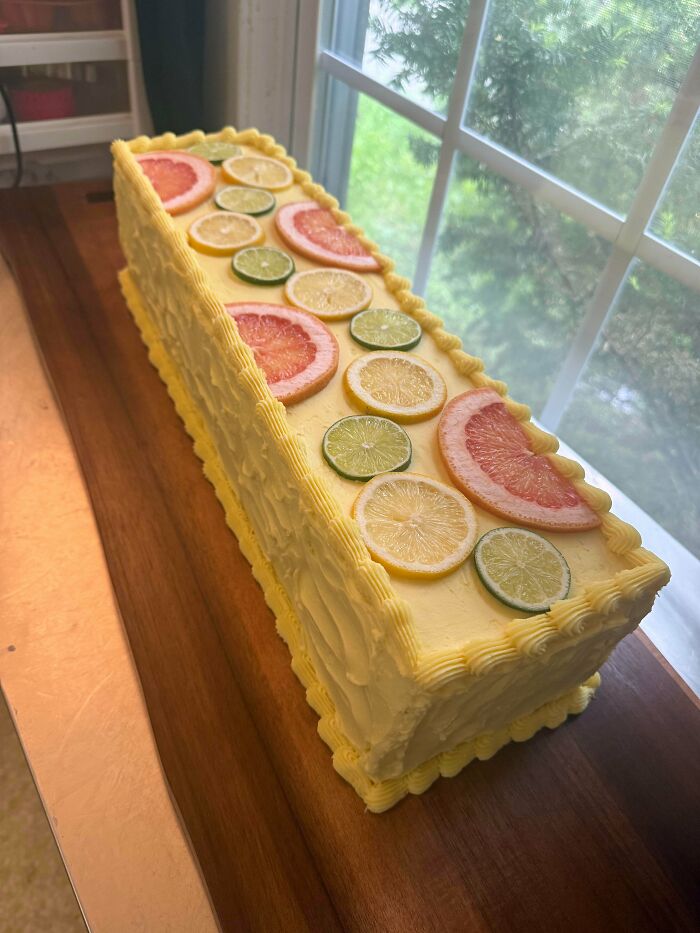Rectangular citrus cake decorated with grapefruit, lemon, and lime slices on yellow frosting