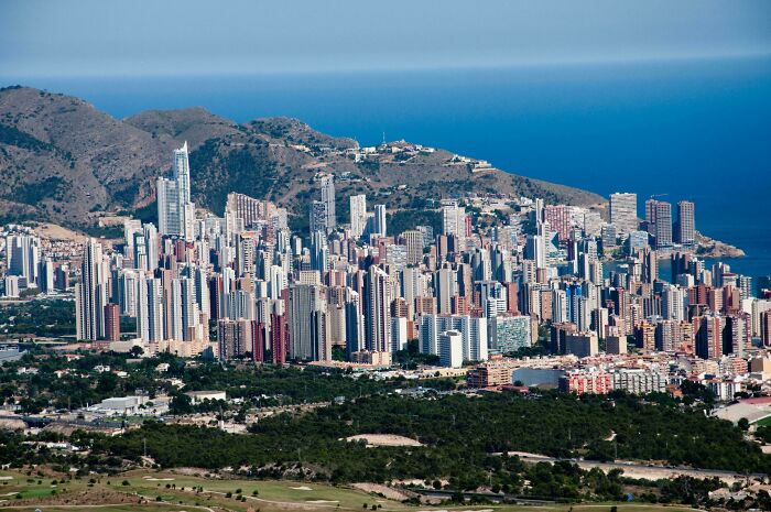 Urban hell cityscape with dense high-rise buildings near mountains and sea