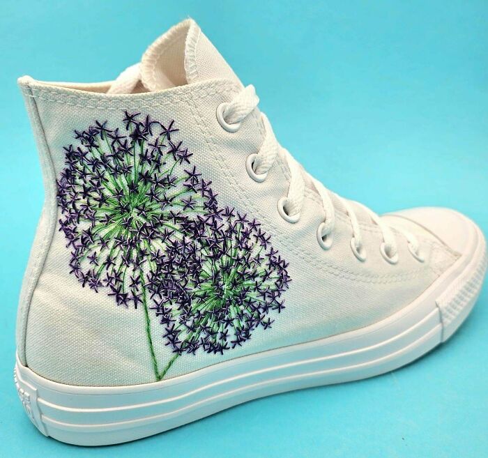 Purple flower embroidery projects hand-stitched onto a white high-top canvas sneaker