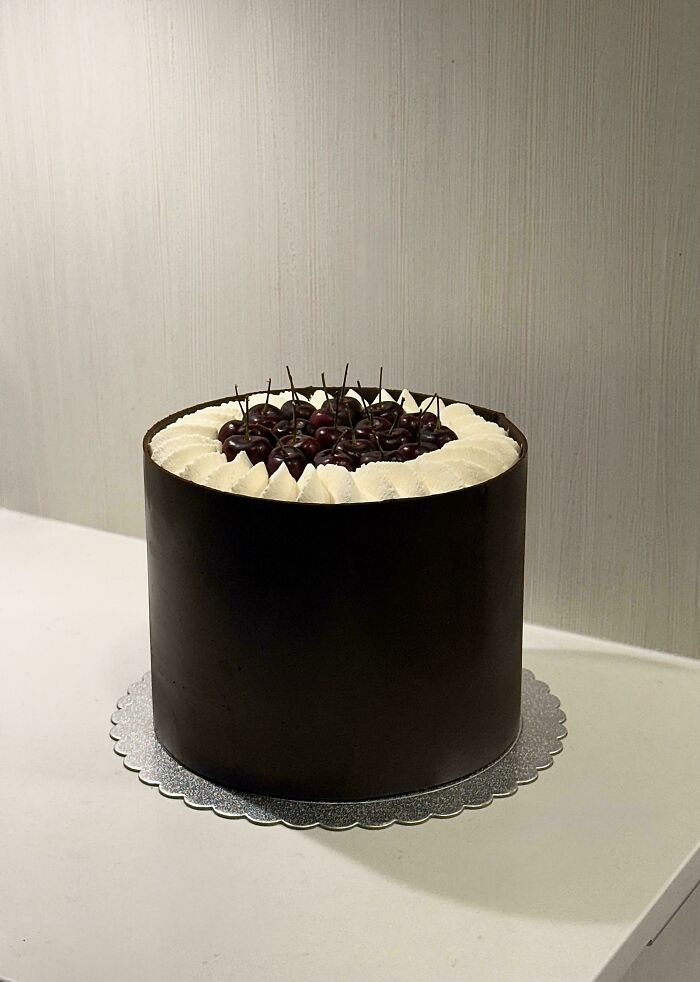 Amazing treats by bakers: A tall dark chocolate cake with whipped cream and cherries on top, a delicious dessert.
