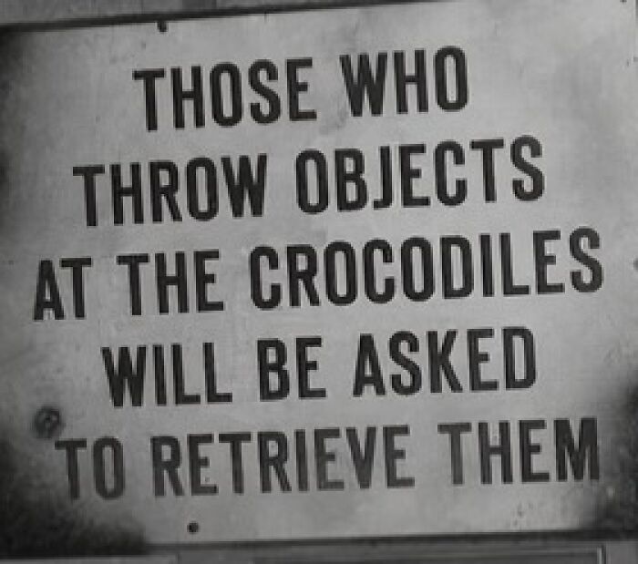 Absurd sign warns those who throw objects at crocodiles must retrieve them