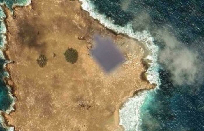 Google Maps satellite image of a small island with a building obscured by pixelation
