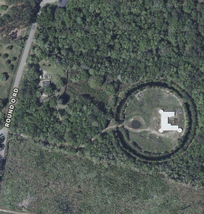 Top-down satellite image of a circular moat and castle structure on Google Maps