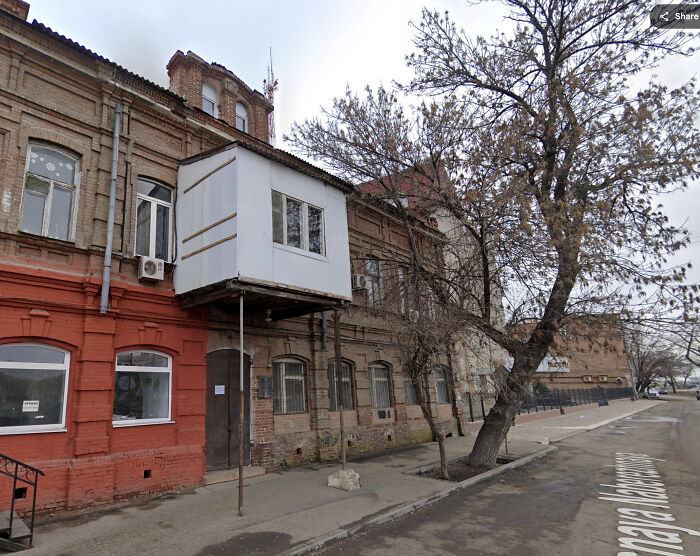 Old building with a precariously supported balcony captured in Google Maps shenanigans