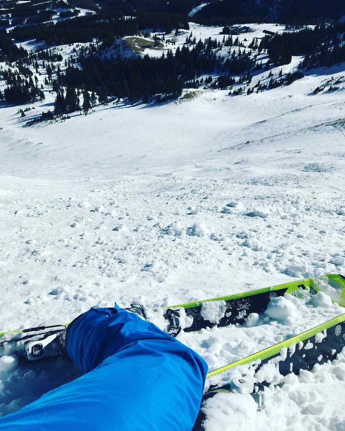 Skier resting with skis on snowy mountain slope with forest background