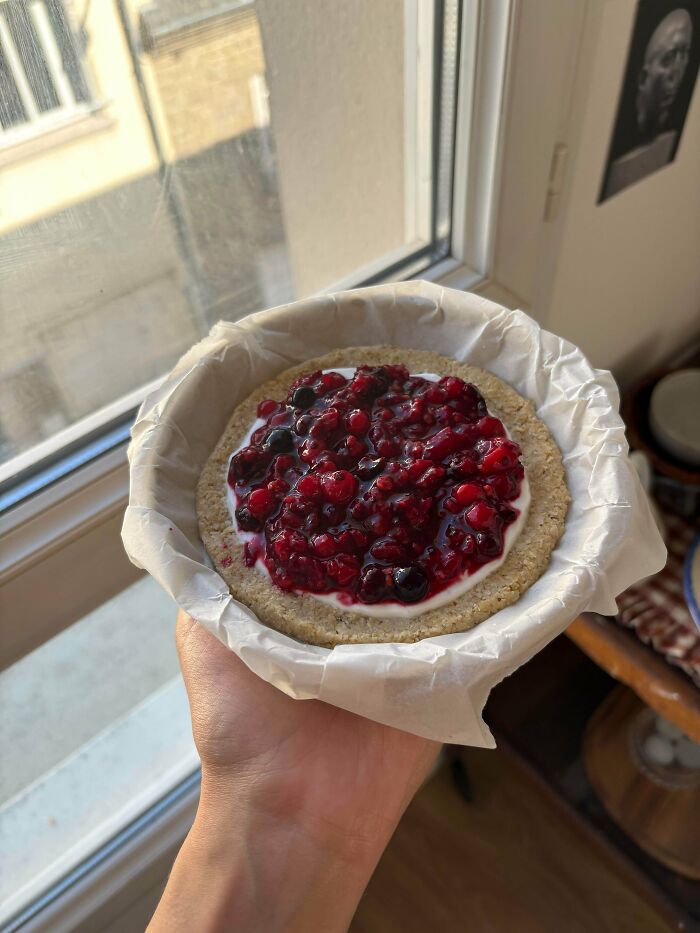 Amazing treats by bakers: A person holds a small, round pastry with berries and cream, a delicious treat.